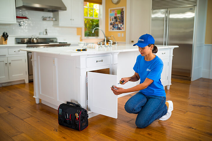 handyperson repairing kitchen cabinet