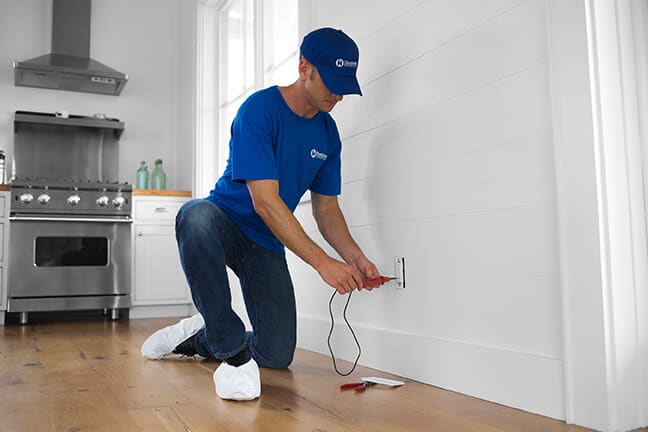 handyman testing electrical outlet in home