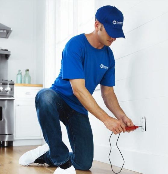 handyman testing electrical outlet in home