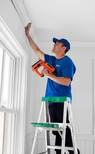 handyman using nail gun to install crown molding