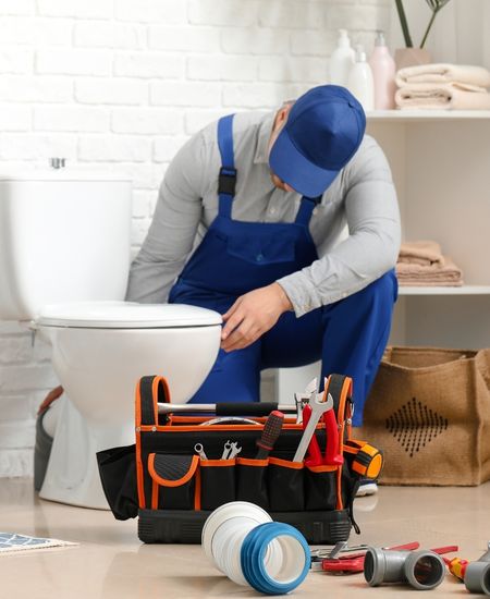 Plumber Repairing Toilet Bowl in Bathroom