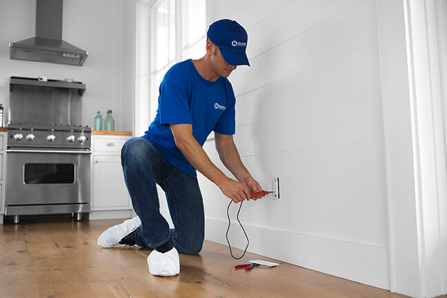 home repair handyman testing electrical outlet in home