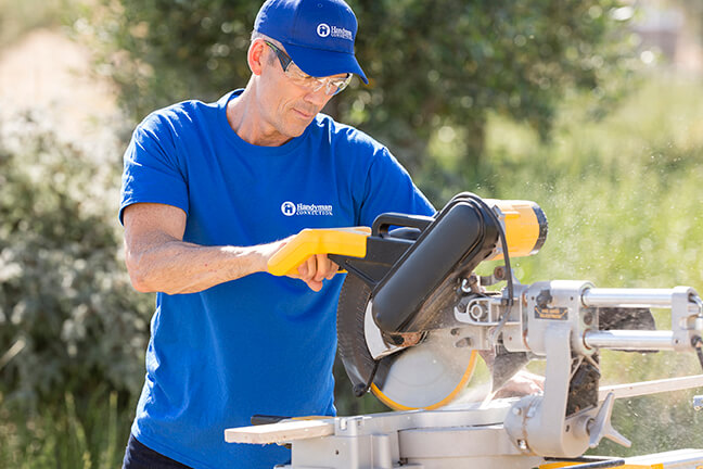 handyman cutting wood with saw