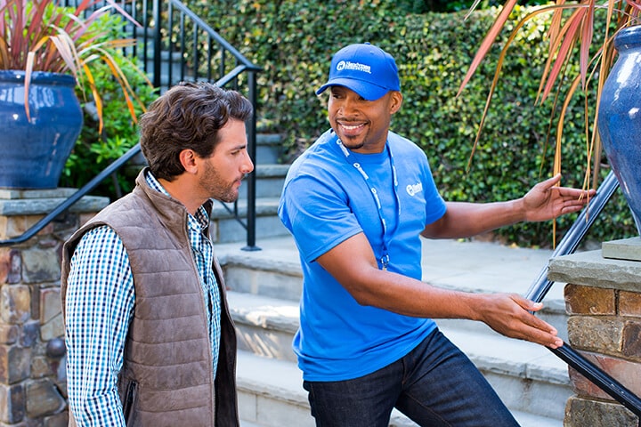 handyman inspecting porch railing with homeowner