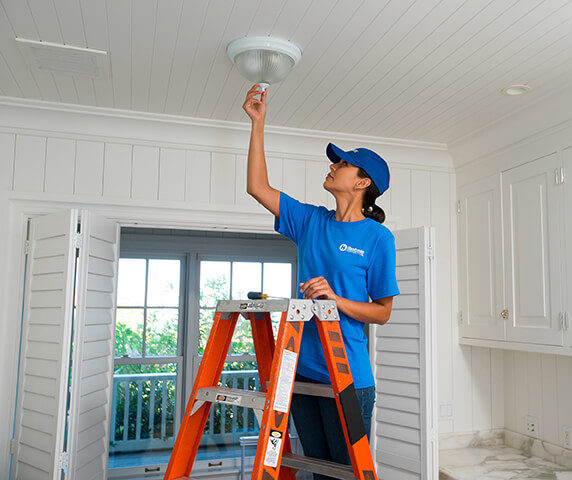 handyperson installing electric light fixture