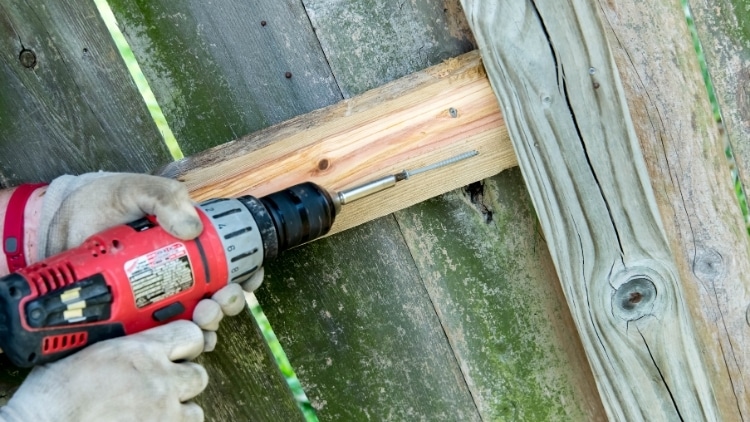 image of a handyman repairing or painting a wooden fence