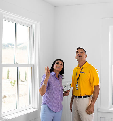 handyman inspecting walls inside home with customer