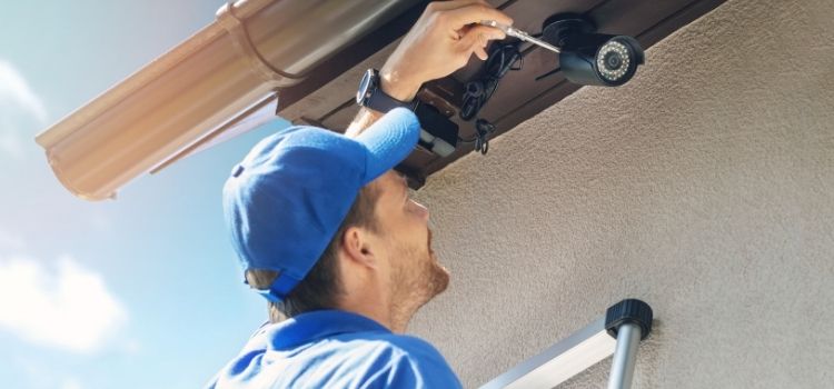 Man install outdoor surveillance camera for home security