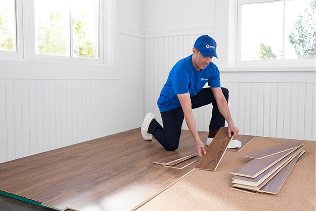 handyman installing hardwood flooring in a home